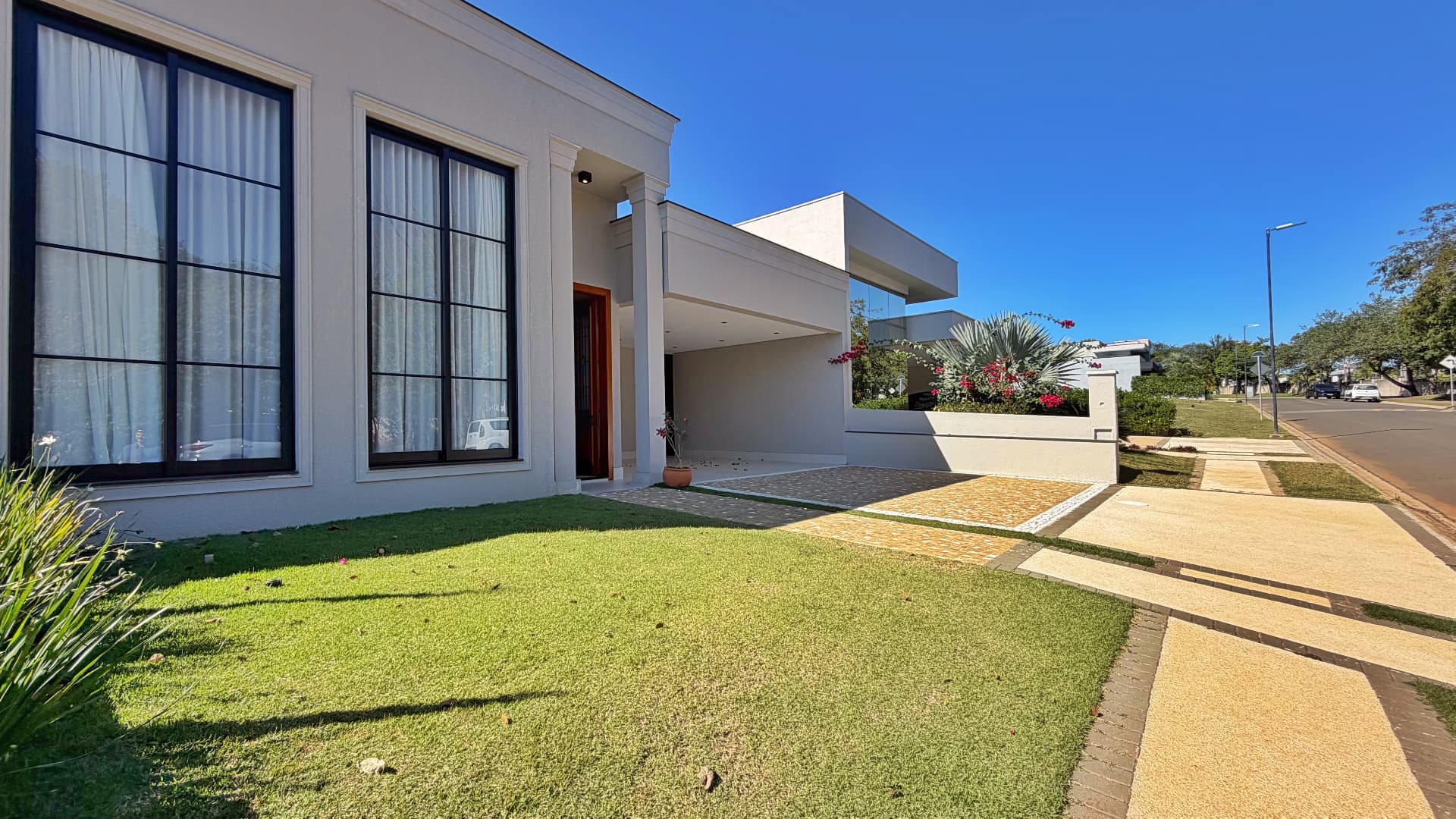 Fachada lateral da Casa D37 com jardim gramado e garagem coberta